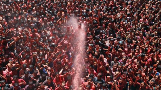 Eine große Menschenmenge wird mit roter Farbe bespritzt.