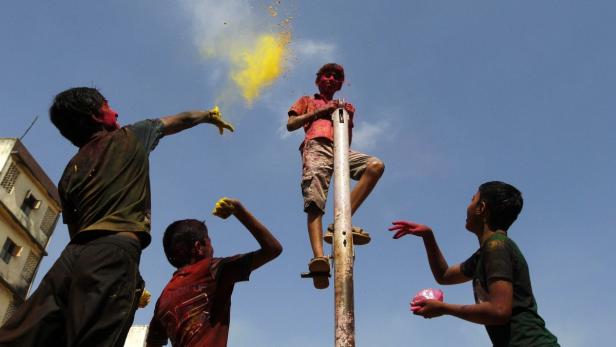 Kinder bewerfen sich während des Holi-Fests mit Farbpulver.