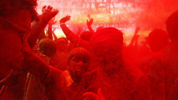 Eine Menschenmenge feiert mit rotem Farbpulver bei einer Holi-Veranstaltung.