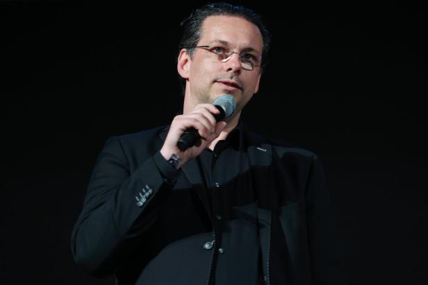 Ein Mann mit Brille spricht in ein Mikrofon.