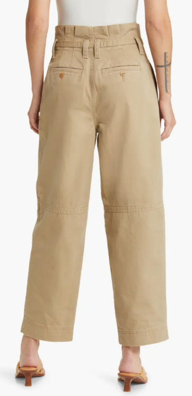 Eine Person trägt eine beigefarbene Paperbag-Hose und Sandalen.