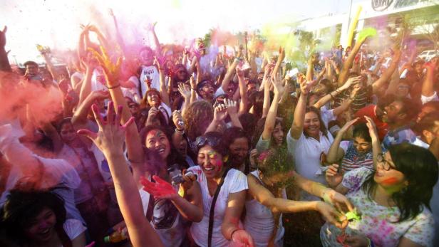 Eine große Gruppe Menschen feiert ein Holi-Fest mit bunten Farben.