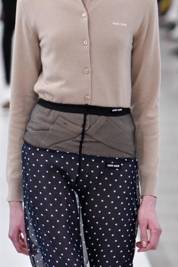 Detailaufnahme eines Outfits von Miu Miu mit Cardigan, Strumpfhose und gepunkteter Hose.