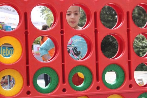 Ein Mädchen schaut durch die Löcher eines roten Spielzeugs.