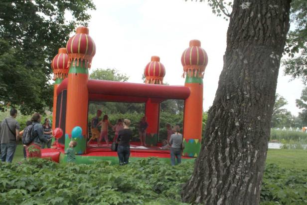 Kinder spielen auf einer Hüpfburg in Form eines Schlosses.