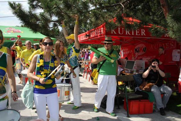Eine Gruppe von Menschen in brasilianischen Farben spielt Musik und feiert im Freien.