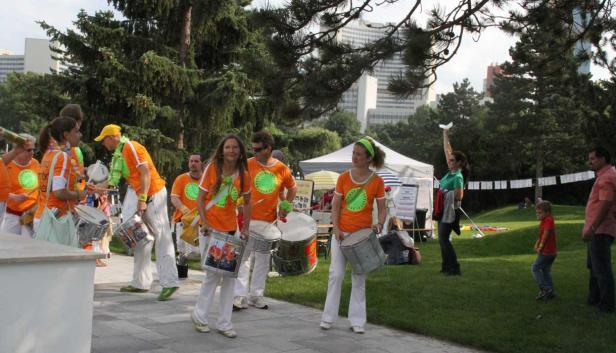 Eine Gruppe von Trommlern in orangefarbenen T-Shirts tritt in einem Park auf.
