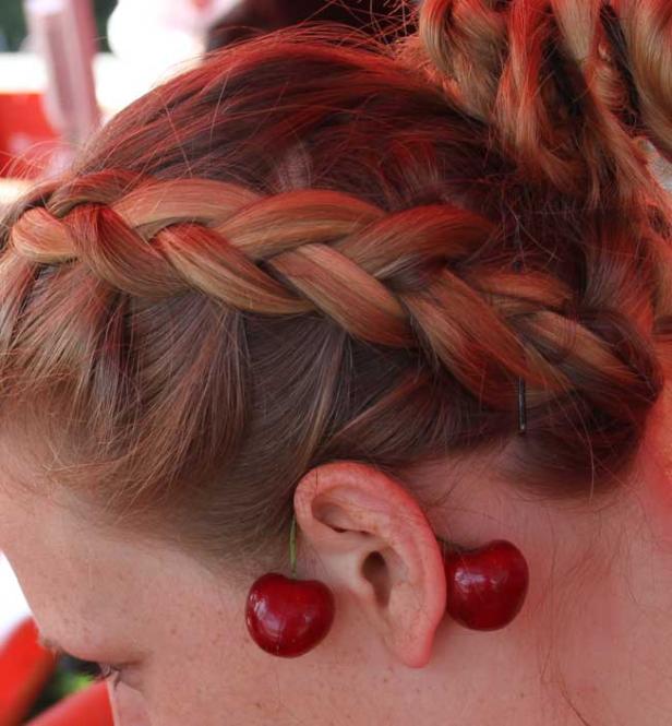 Eine Frau trägt Kirschen als Ohrringe.