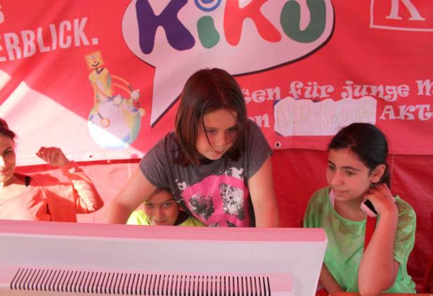 Mehrere Kinder stehen an einem Stand mit der Aufschrift „KiKo“.