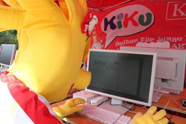 Ein gelbes Maskottchen tippt auf einer Computertastatur vor einem „KiKu“-Banner.