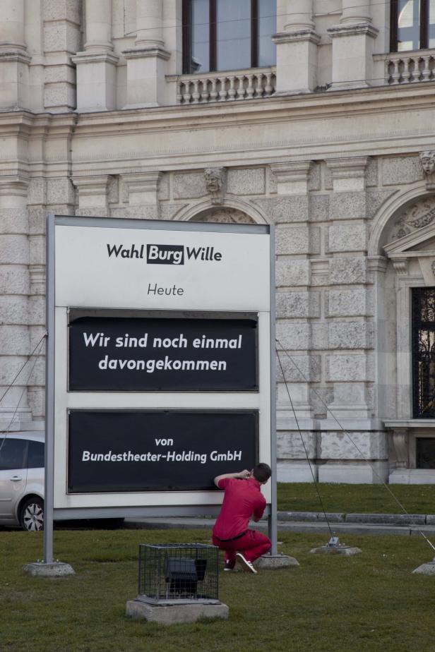 Ein Mann in roter Kleidung arbeitet an einer Anzeigetafel der Bundestheater-Holding GmbH.