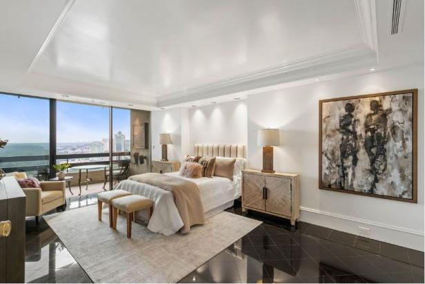 Ein Schlafzimmer mit einem Bett, Nachttischen und einem Balkon mit Blick auf die Stadt.