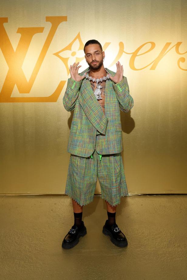 Maluma posiert vor einem goldenen Louis Vuitton-Hintergrund.
