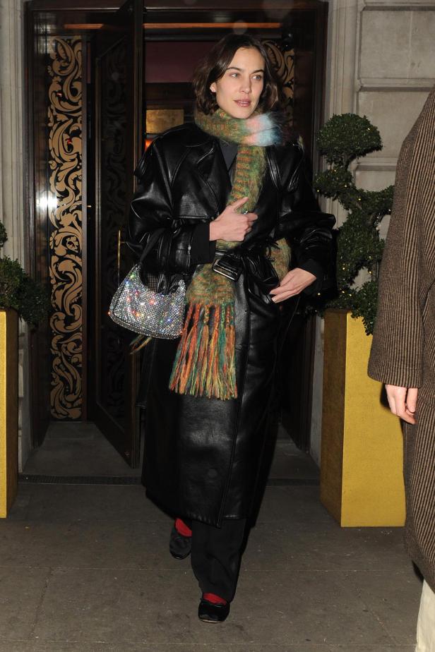 Alexa Chung trägt Ballerinas mit Socken und einen langen Ledermantel.