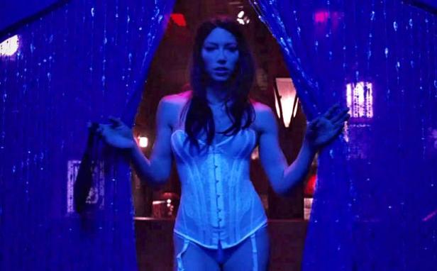 Jessica Biel in einem weißen Korsett, umgeben von blauem Licht und Vorhängen.