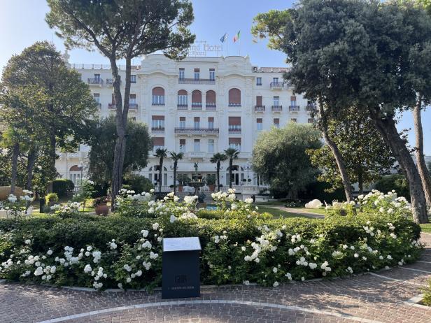 Das Grand Hotel Rimini mit einem Garten voller weißer Rosen im Vordergrund.