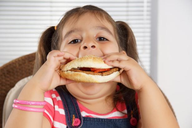 Close-up of Caucasian girl with pigtails eating a burger