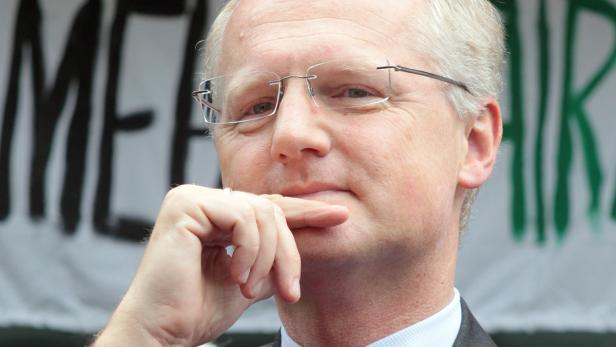 Ein Mann mit Brille hält seine Hand an sein Kinn.