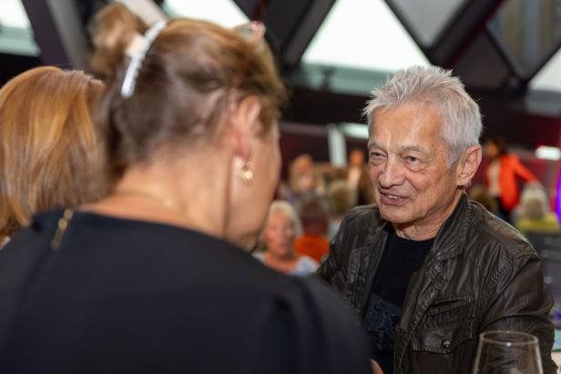 Ein älterer Mann mit grauen Haaren unterhält sich mit einer Frau.