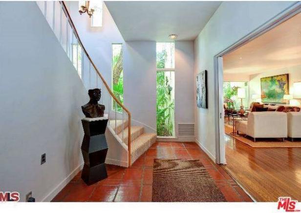Ein Flur mit Treppe, einer Skulptur und Blick in ein Wohnzimmer.