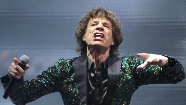 Mick Jagger tritt in einem glitzernden grünen Jackett auf der Bühne auf.