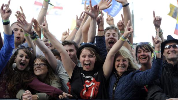 Eine Menschenmenge jubelt mit erhobenen Händen auf einem Musikfestival.