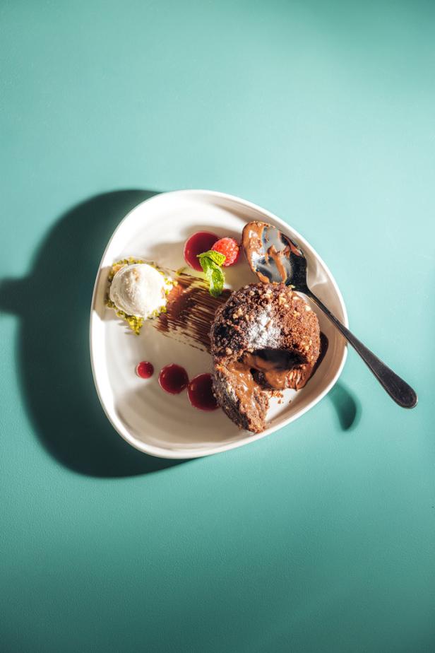 Ein Schokoladenküchlein mit flüssigem Kern, Eis und Himbeeren auf einem Teller.