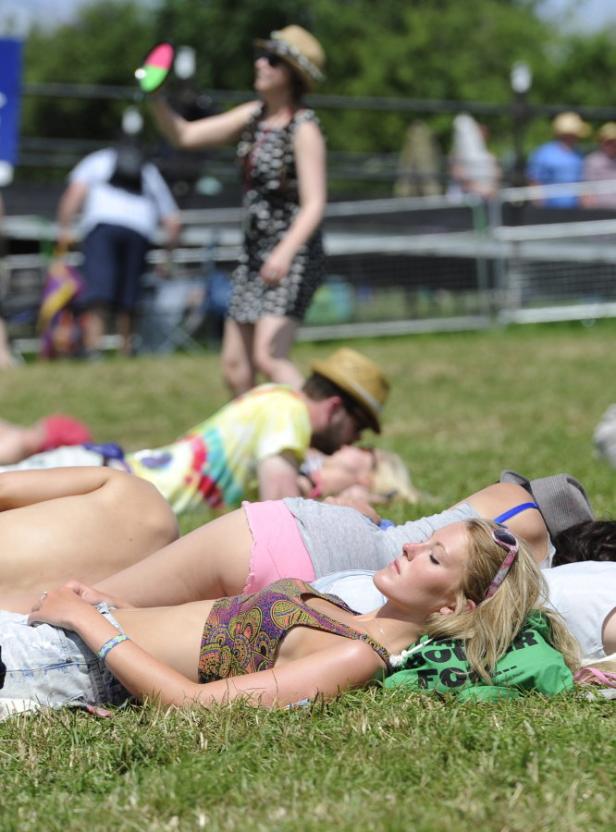Mehrere Personen entspannen sich auf einer Wiese, einige liegen im Gras.