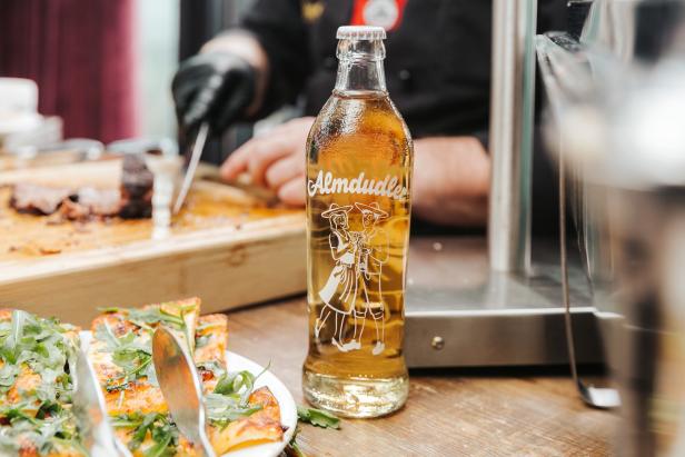 Eine Flasche Almdudler steht auf einem Tisch mit Speisen.