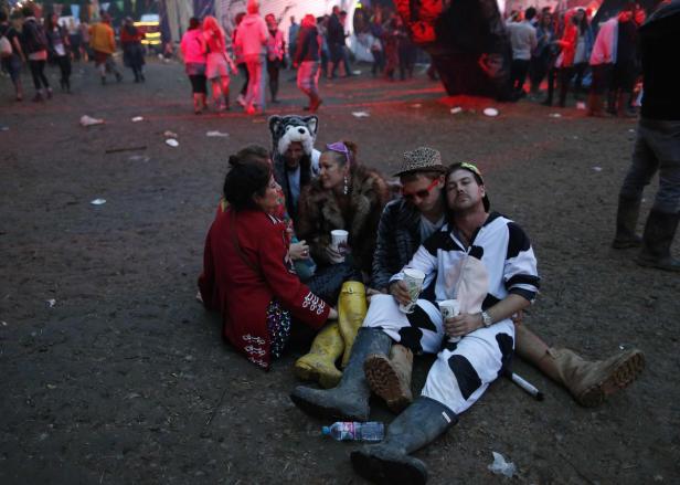 Eine Gruppe von Festivalbesuchern sitzt auf dem schlammigen Boden.