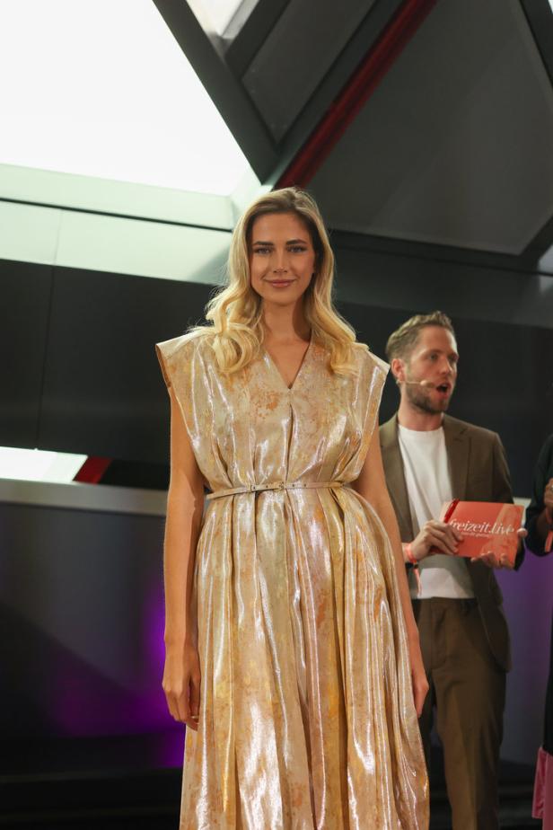 Eine Frau in einem goldenen Kleid auf einer Veranstaltung.
