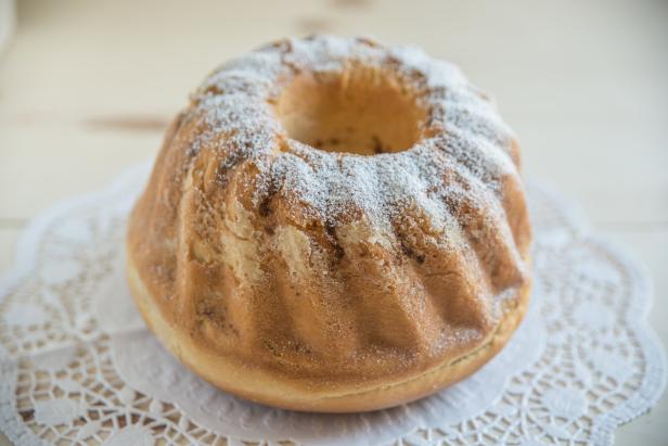 Ein Gugelhupf mit Puderzucker auf einer weißen Tortenspitze.