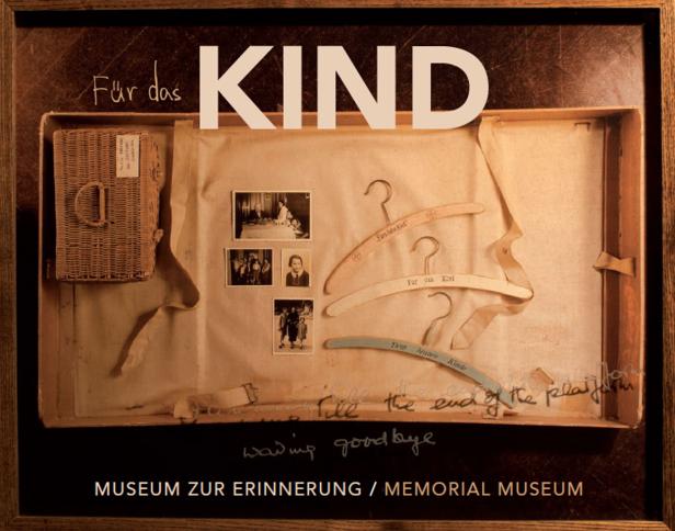 Eine Vitrine mit Kinderfotos, Kleiderbügeln und einem Korb im Museum zur Erinnerung.