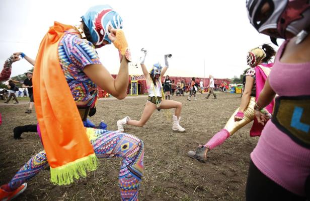 Mehrere als Wrestler verkleidete Personen posieren auf einem Festivalgelände.