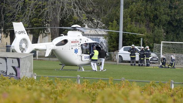 Ein Rettungshubschrauber steht auf einem Feld, während Sanitäter und Feuerwehrleute in der Nähe sind.