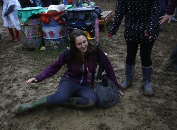Eine Frau sitzt im Schlamm, möglicherweise auf einem Festival.