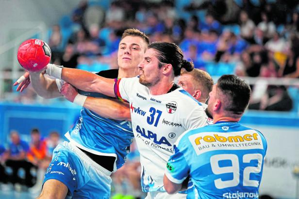 Zwei Handballspieler kämpfen um den Ball während eines Spiels.