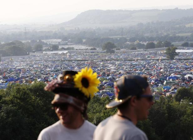 Blick über ein riesiges Zeltlager auf einem Festivalgelände mit zwei Personen im Vordergrund.