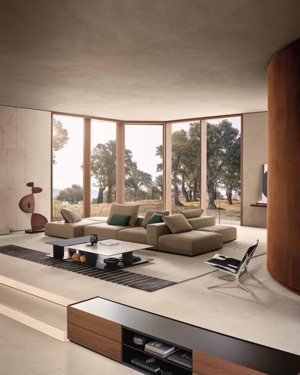 Ein modernes Wohnzimmer mit einem modularen Sofa und Blick auf eine Baumlandschaft.