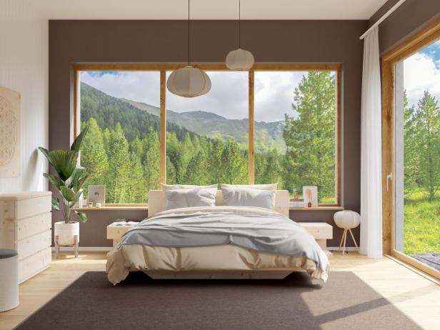 Ein helles Schlafzimmer mit großem Fenster und Blick auf einen bewaldeten Berghang.
