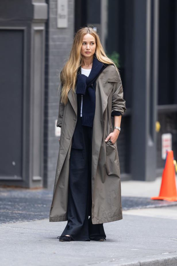 Jennifer Lawrence trägt einen langen Trenchcoat und einen Schal auf der Straße.