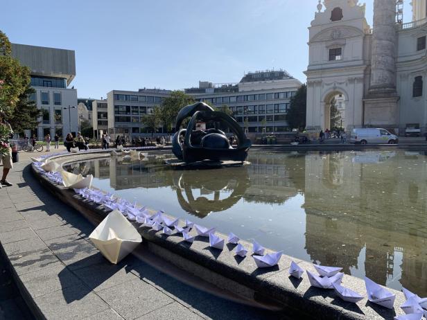 Kleine Papierboote umranden den Teich vor der Karlskirche.