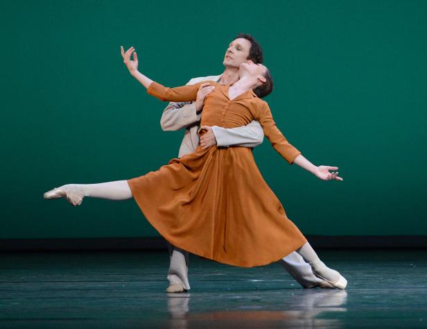 Ein Balletttänzerpaar führt eine anmutige Hebefigur auf einer Bühne auf.