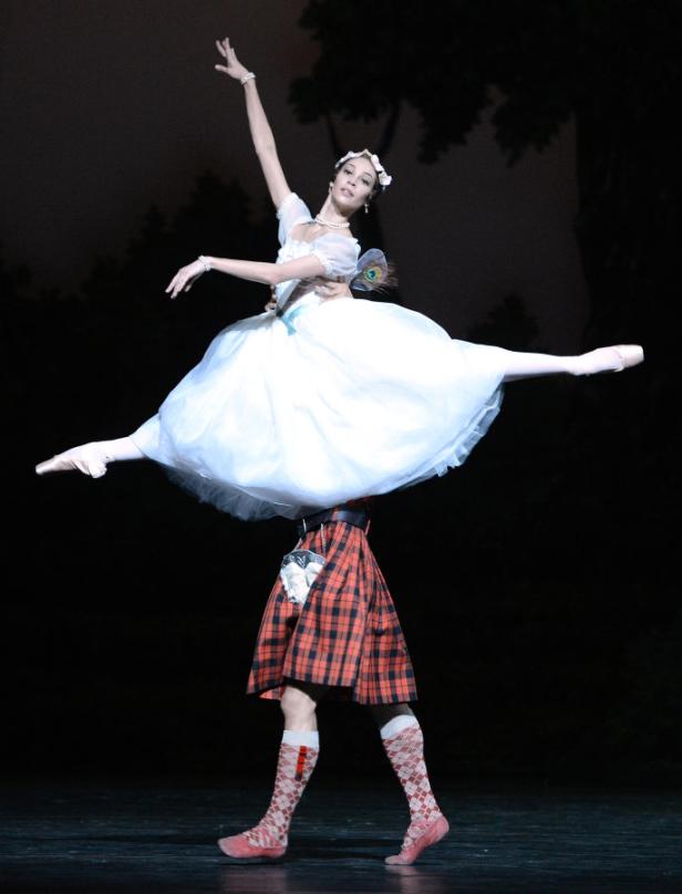 Eine Ballerina in einem weißen Tutu wird von einem Tänzer im Schottenrock gehoben.