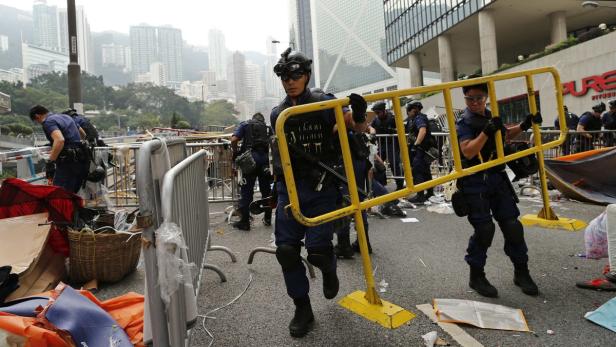 Polizisten räumen in Hongkong Barrikaden und Trümmer von der Straße.
