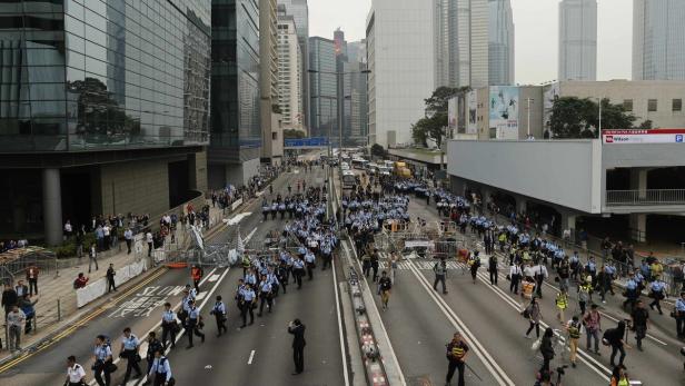 Eine große Gruppe von Polizisten marschiert eine Straße in einer Stadt entlang.