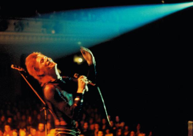 David Bowie tritt auf einer Bühne vor einem Publikum auf.