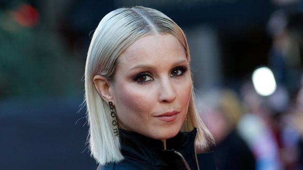 Nahaufnahme von Sängerin Ellie Goulding mit blondem Bob und auffälligen Ohrringen.