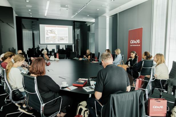 Eine Gruppe von Personen sitzt an einem Tisch während einer Präsentation von CEWE Fotoservice.