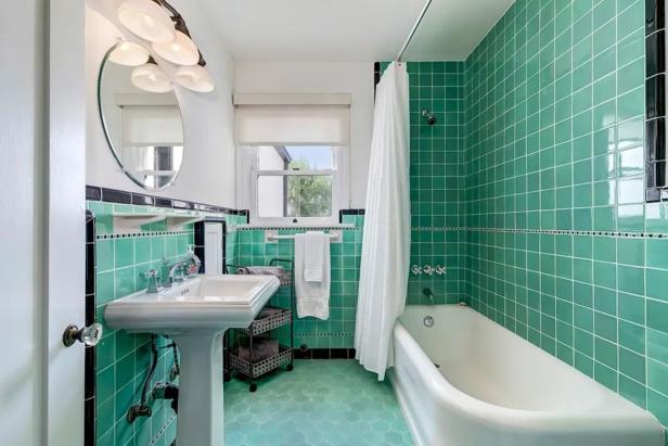 Ein Badezimmer mit grünen Fliesen, einer Badewanne und einem Waschbecken.